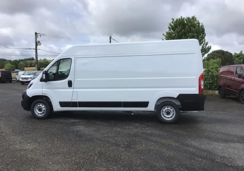 Profil côté gauche d’un FIAT Ducato Fourgon blanc 2023, avec bande noire basse et roues acier simples.