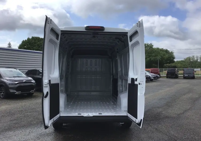 Vue arrière d'un FIAT Ducato Fourgon blanc 2023 avec portes ouvertes montrant l'espace de chargement vide.