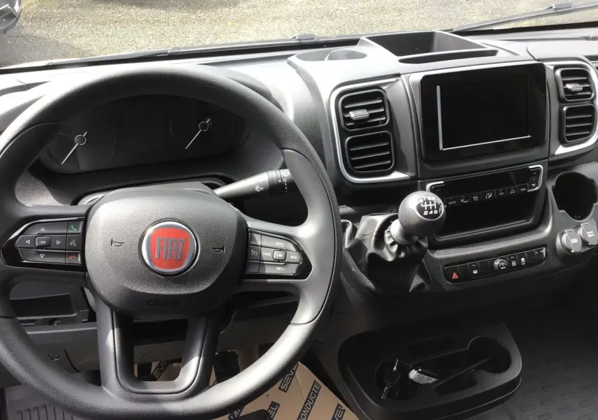 Vue intérieure du tableau de bord et volant du Fiat Ducato Fourgon 2023 avec boîte manuelle et écran tactile central.
