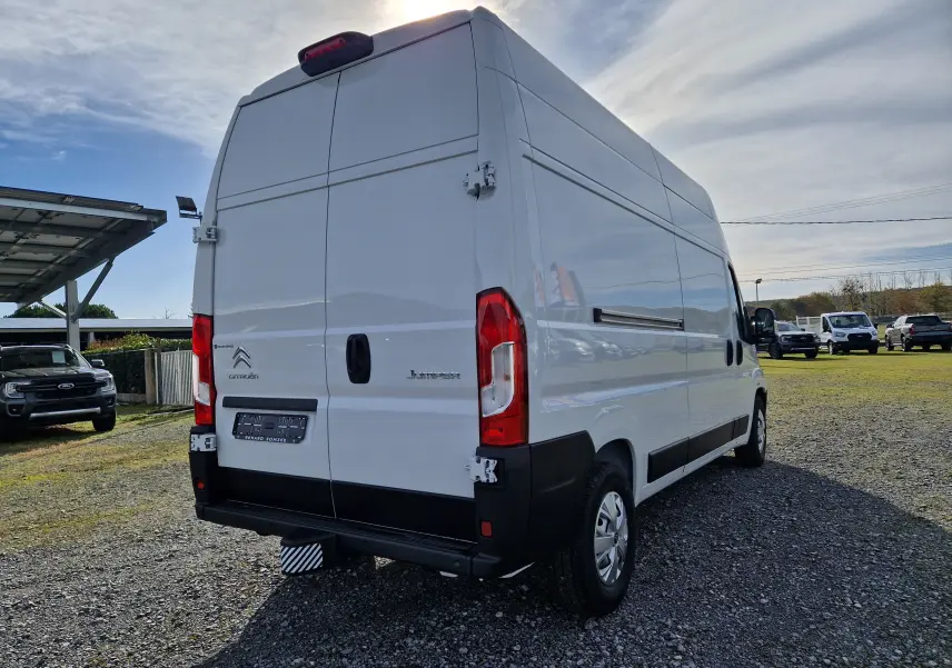 Vue 3/4 arrière droite d'un utilitaire blanc Citroën Jumper L3H3 2023 avec hayon et feux arrière rouges.
