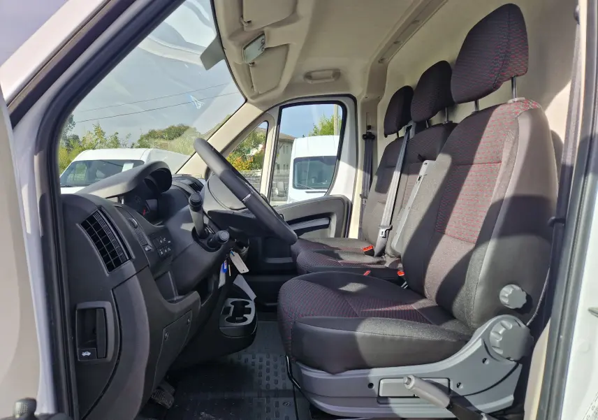 Vue intérieure côté conducteur du Citroën Jumper blanc 2023, montrant les sièges avant et le tableau de bord.