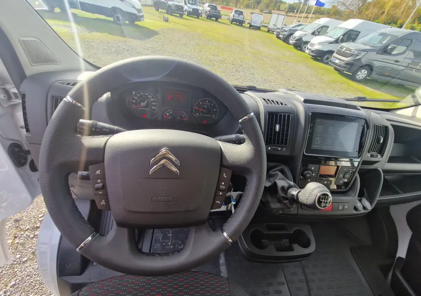 Vue intérieure du poste de conduite du Citroën Jumper blanc 2023 avec volant, tableau de bord et levier de vitesses manuel.