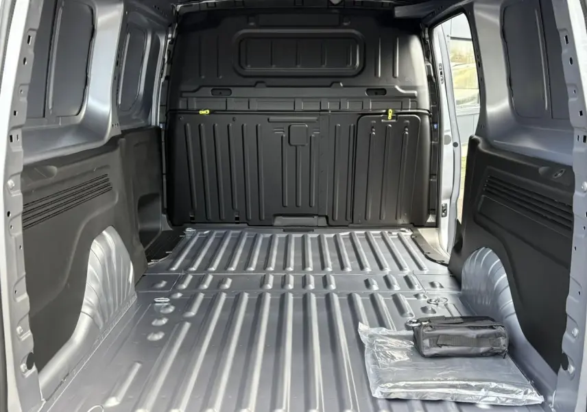 Vue intérieure arrière du Citroën Berlingo Van XL gris Artense montrant l'espace de chargement vide avec un kit posé au sol.