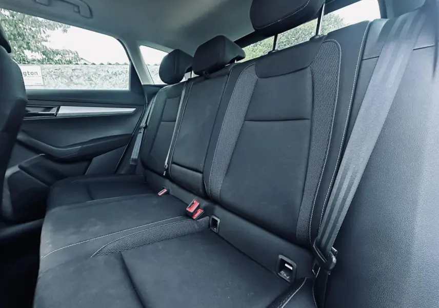Vue intérieure de la banquette arrière noire du Skoda Karoq 2024, avec ceintures et appuie-têtes visibles.