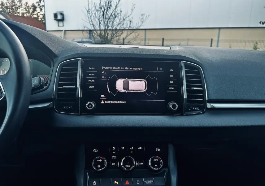 Vue intérieure du tableau de bord du Skoda Karoq 2024 avec écran tactile affichant l'aide au stationnement.