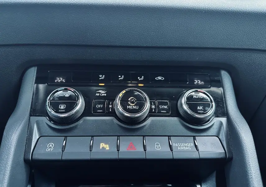Vue rapprochée de la console centrale noire du Skoda Karoq blanc 2024, avec commandes climatisation et boutons fonctionnels.