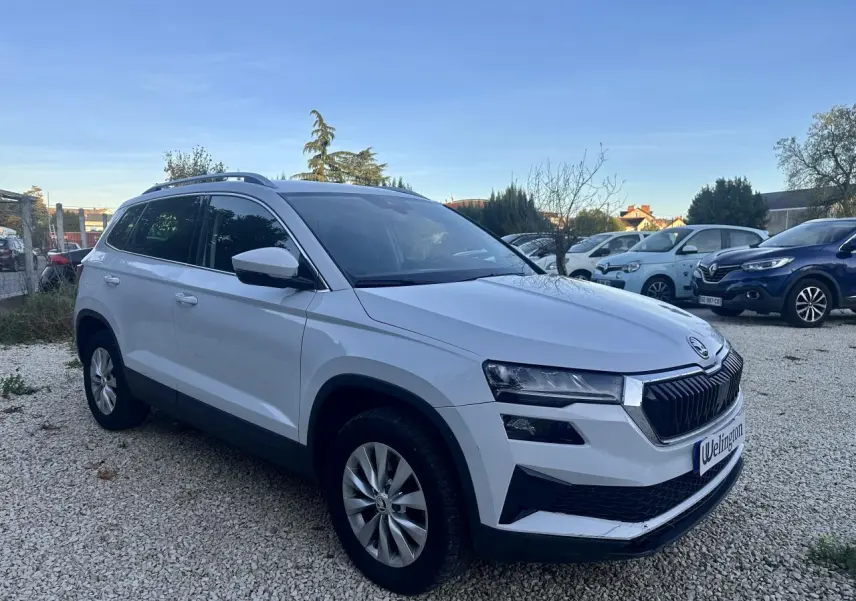 Vue 3/4 avant gauche d’un Skoda Karoq blanc 2024 avec calandre noire et jantes alliage argentées.