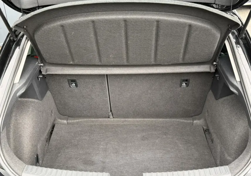 Coffre ouvert vu de l'arrière d'une SEAT LEON noir Minuit, montrant l'espace de chargement vide et la plage arrière relevée.