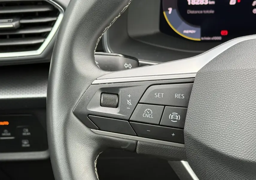 Gros plan sur le volant cuir multifonction côté gauche du SEAT LEON 2.0 TDI 115 Style avec commandes de régulateur.