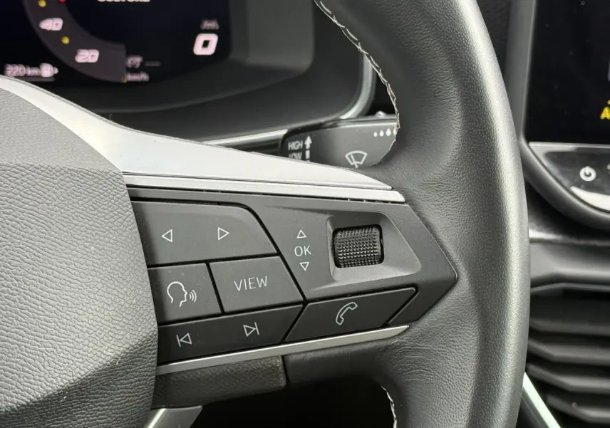 Gros plan sur les commandes multifonctions du volant cuir noir de la SEAT LEON 2025, version 2.0 TDI Style.