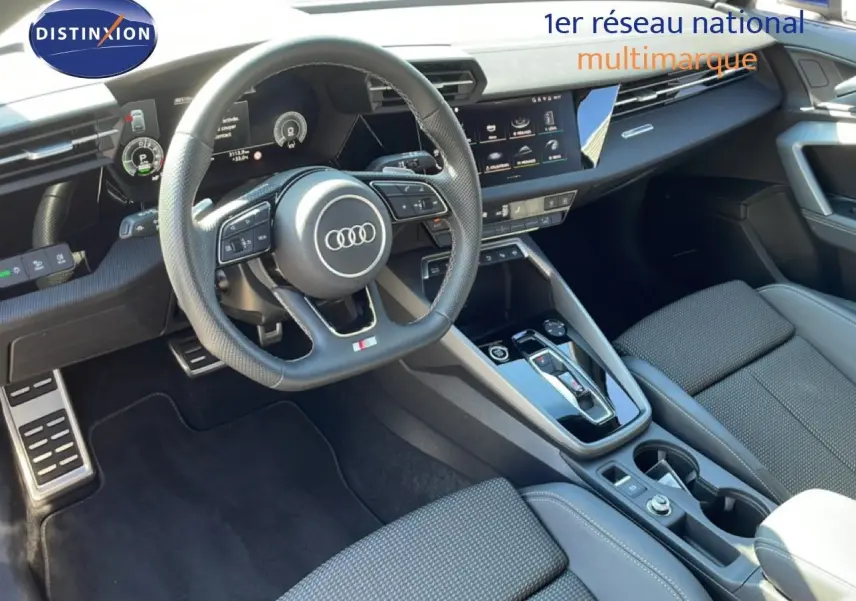 Vue intérieure de l'Audi A3 Sportback 2025, tableau de bord et volant cuir noir avec écran tactile central.