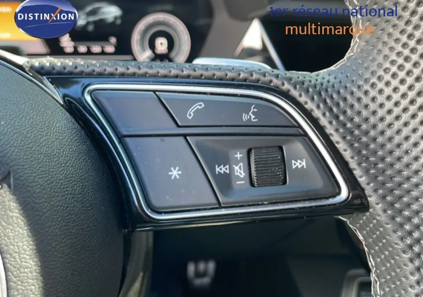 Gros plan sur les commandes du volant en cuir perforé de l'Audi A3 Sportback bleu Navarre, version hybride rechargeable 2025.