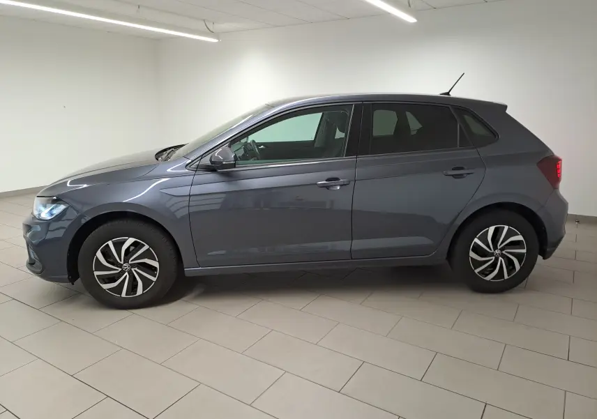Volkswagen Polo gris cendre vue de profil côté gauche dans un intérieur lumineux avec jantes distinctives.