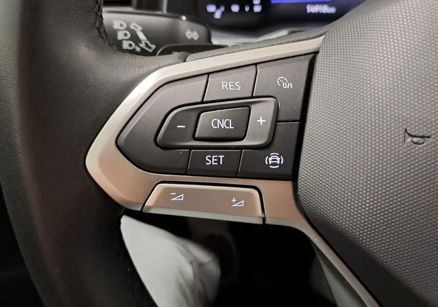 Gros plan sur les commandes de régulateur de vitesse au volant d'une Volkswagen Polo gris cendre 2025.