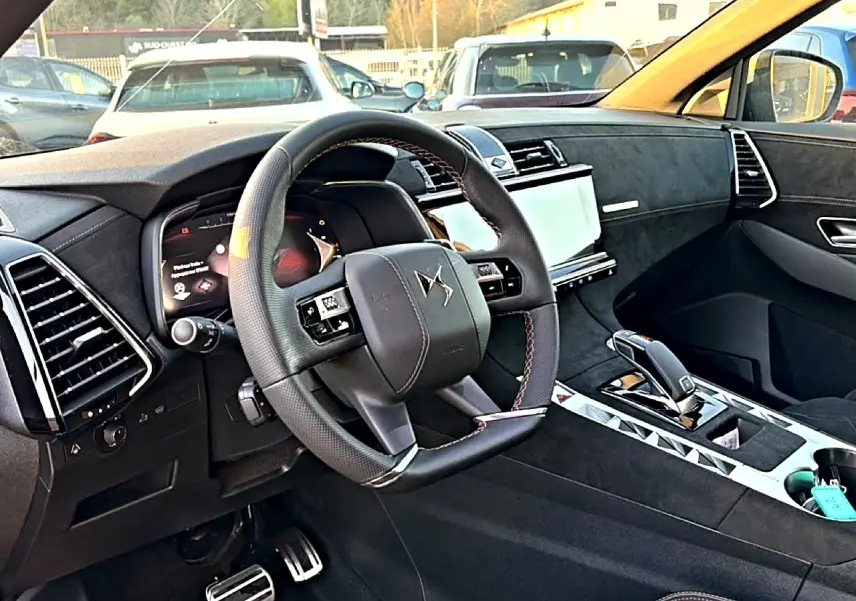 Vue intérieure côté conducteur du DS7 1.5 BlueHDi noir, volant cuir avec surpiqûres rouges et écran tactile central.