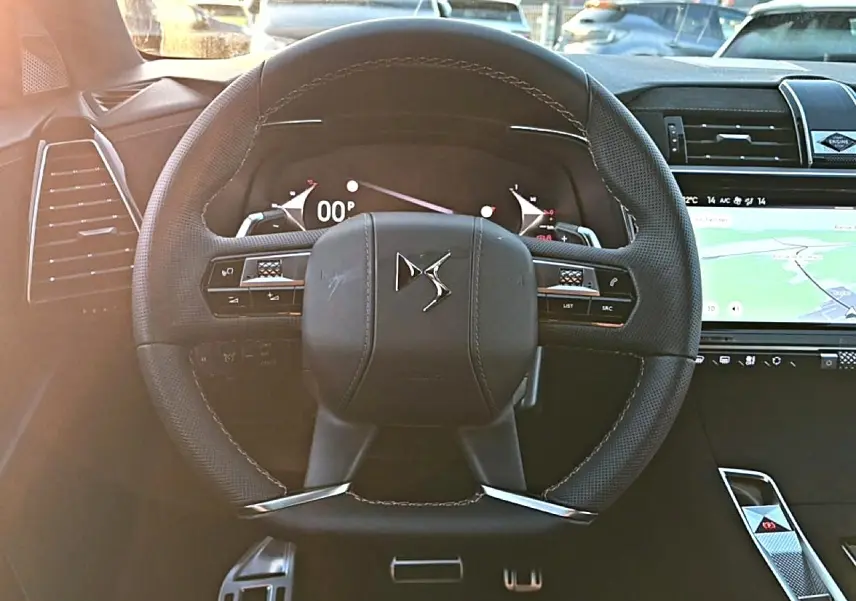 Vue rapprochée du volant cuir noir DS7 2026 avec commandes intégrées et tableau de bord numérique lumineux.