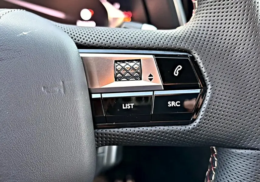 Gros plan sur les commandes noires et argentées au volant en cuir perforé du DS7 1.5 BlueHDi 130 Performance Line noir.