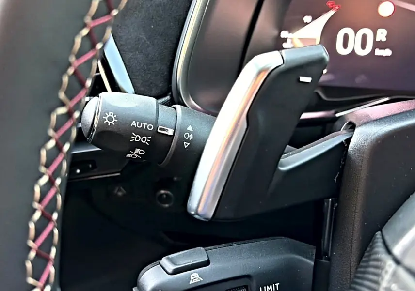 Détail intérieur côté gauche du volant cuir noir avec palettes de changement de vitesse et commandes d’éclairage DS7 noir.