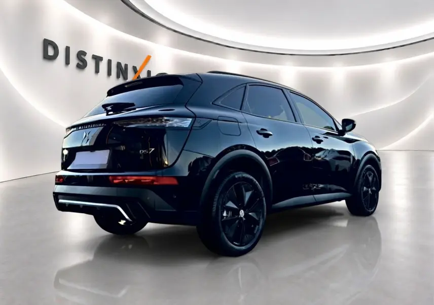 Vue 3/4 arrière droite du SUV DS7 noir brillant avec jantes noires dans un showroom lumineux.