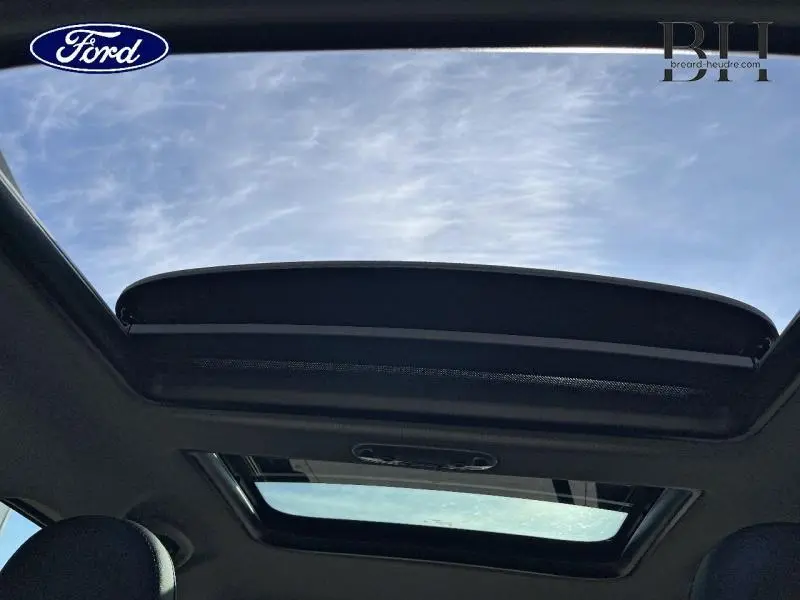 Toit ouvrant panoramique ouvert vu de l'intérieur d'une MINI Countryman Moonwalk Grey, ciel bleu en arrière-plan