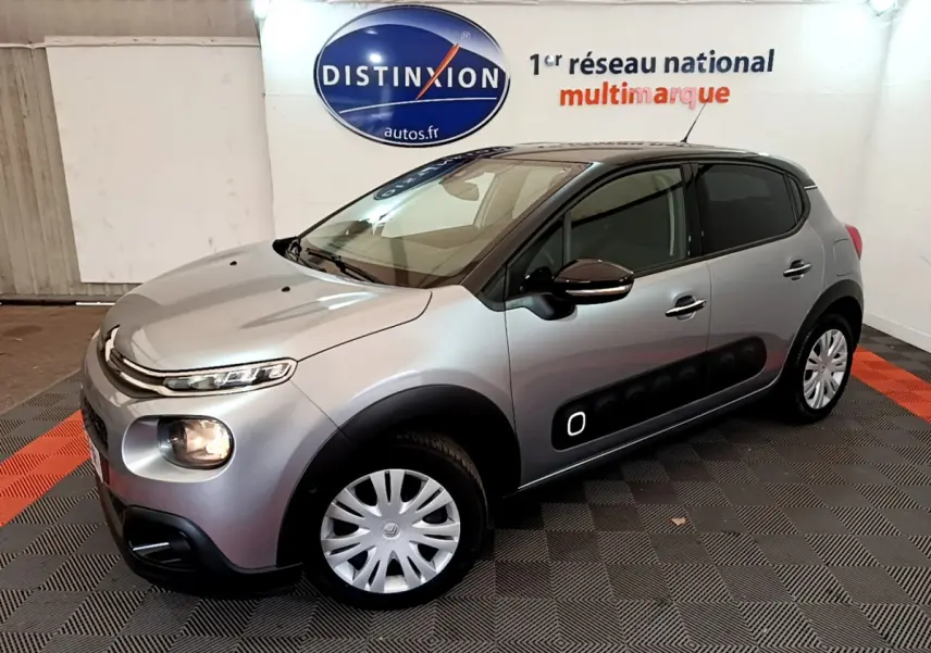 Citroën C3 gris clair vue 3/4 avant droit, avec protections latérales noires et jantes acier.