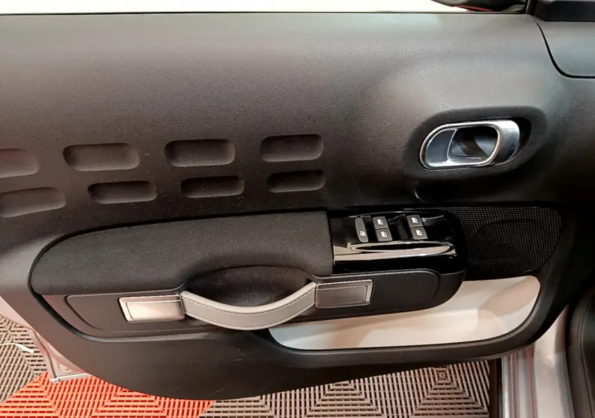 Vue rapprochée de la porte côté droit de la Citroën C3 gris clair, avec commandes de vitres et poignée intégrée.