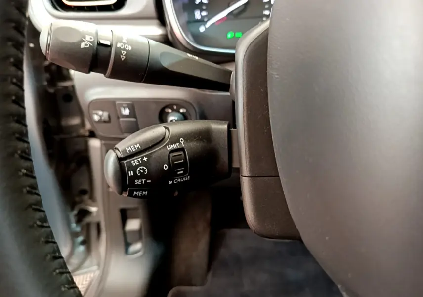 Gros plan sur les commandes de régulateur de vitesse et limiteur côté gauche du volant d'une Citroën C3 gris clair 2019.
