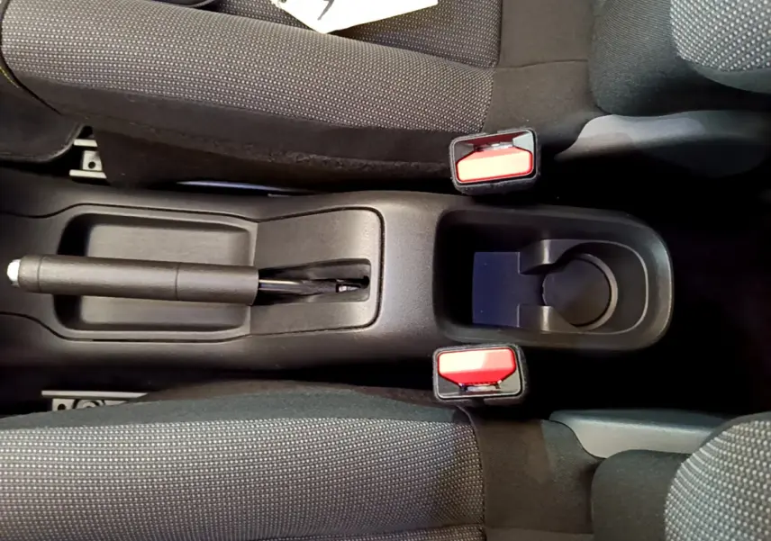 Vue plongeante sur la console centrale de la Citroën C3 2019, montrant frein à main et porte-gobelets entre sièges gris foncé.