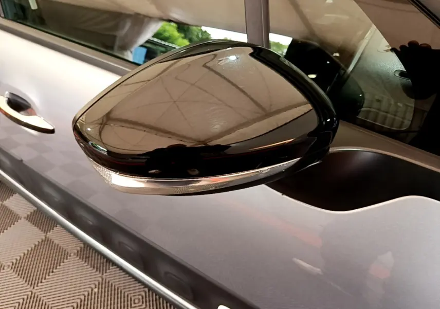 Rétroviseur noir brillant côté gauche d'une Citroën C3 gris clair, avec clignotant intégré visible.