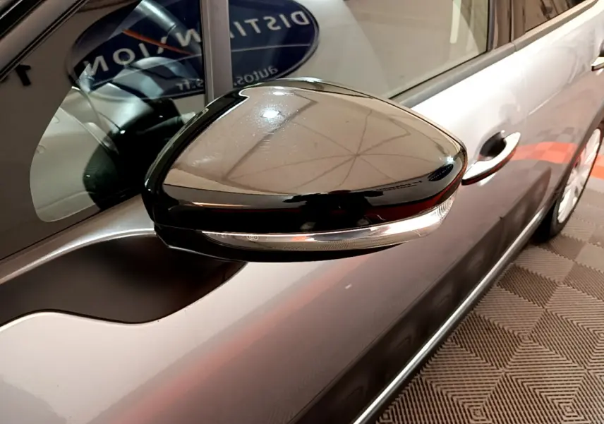 Rétroviseur noir brillant côté gauche d'une Citroën C3 gris clair, avec poignée de porte visible en arrière-plan.