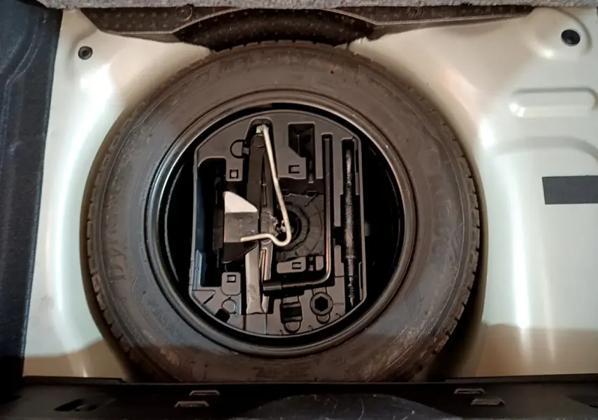 Vue plongeante sur la roue de secours et son rangement dans le coffre d'une Citroën C3 gris clair 2019.