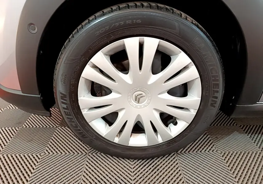 Gros plan sur la roue avant droite grise d'une Citroën C3 2019 avec jante acier et enjoliveur blanc à rayons fins.