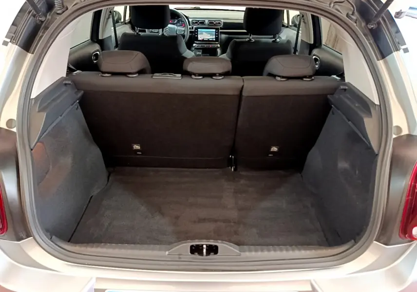 Coffre ouvert vu de l'arrière d'une Citroën C3 gris clair, montrant l'espace de chargement et l'intérieur noir.