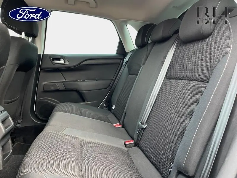 Vue intérieure côté droit montrant la banquette arrière noire en tissu avec ceintures de sécurité et appuie-têtes.