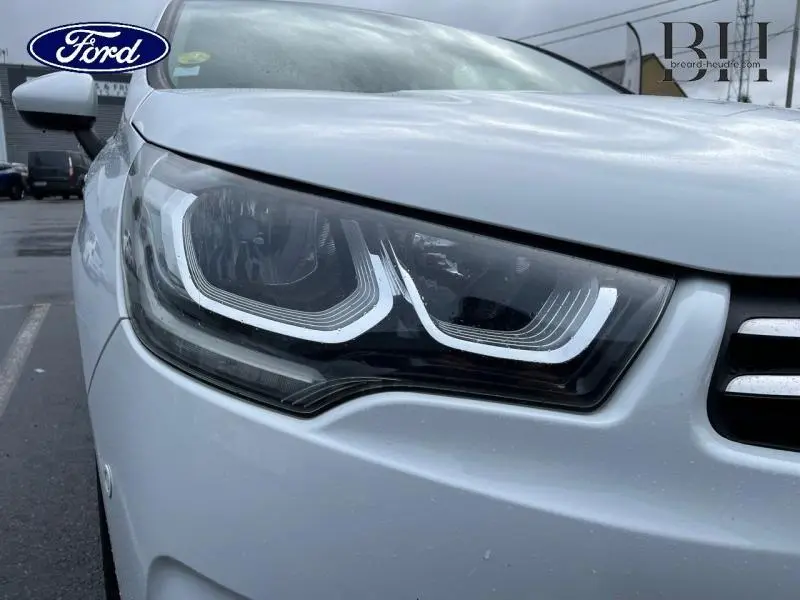 Gros plan sur le phare avant gauche blanc d'une Citroën C4 Millenium Business de 2017, avec calandre partielle visible.