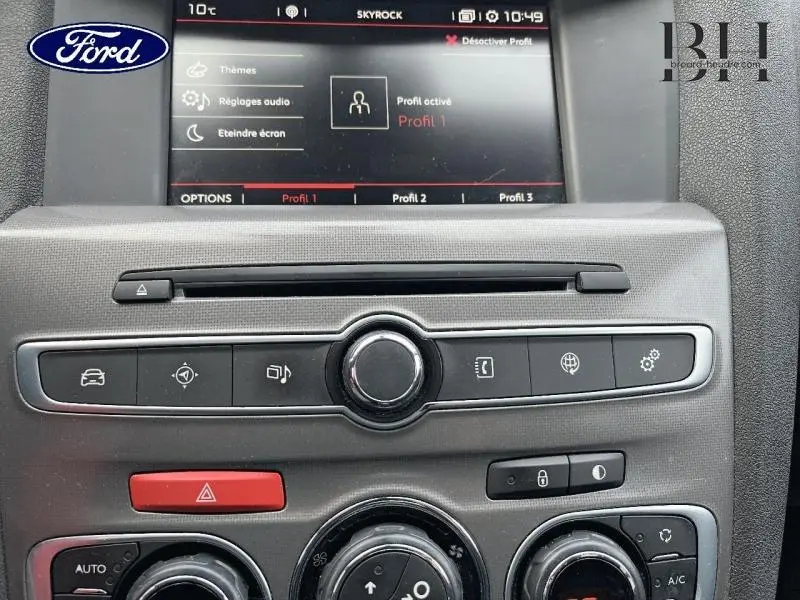 Tableau de bord central avec écran tactile et commandes multimédia d'une Citroën C4 blanche, vue intérieure frontale.