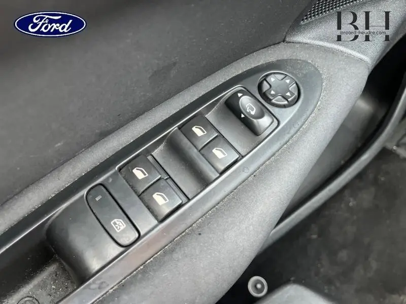 Gros plan sur les commandes de lève-vitres et rétroviseurs côté conducteur d'une Citroën C4 blanche, intérieur noir.