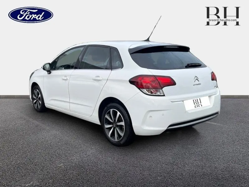 Vue 3/4 arrière droite d'une Citroën C4 blanche de 2017 avec jantes alu et lunette arrière surteintée.