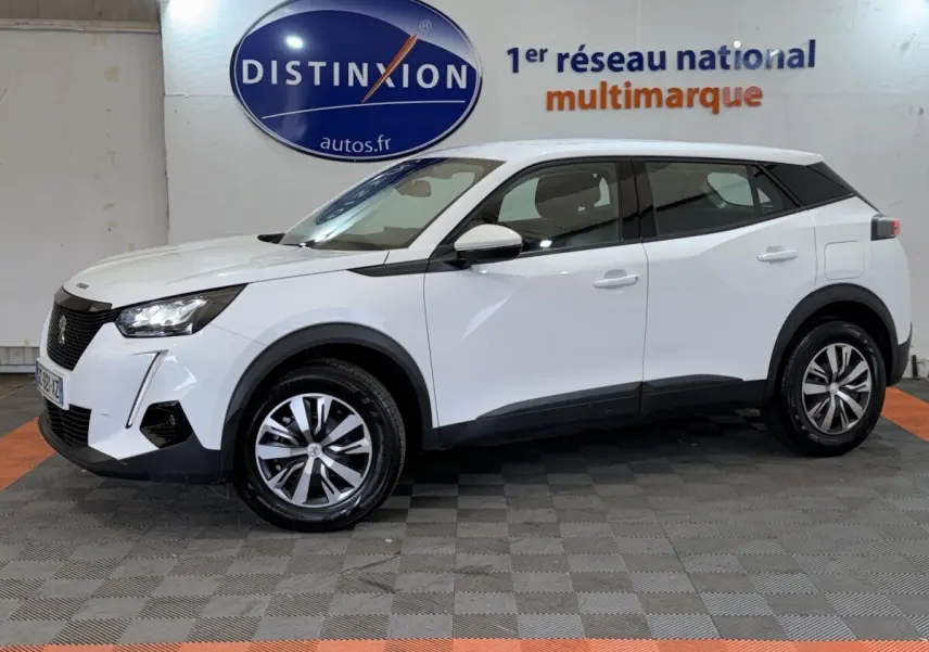Peugeot 2008 blanc en profil droit, avec jantes alliage et détails noirs contrastants sous éclairage intérieur showroom.