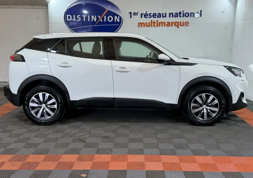 Peugeot 2008 blanc vue de profil côté gauche, avec jantes alliage et toit noir contrastant en intérieur showroom.