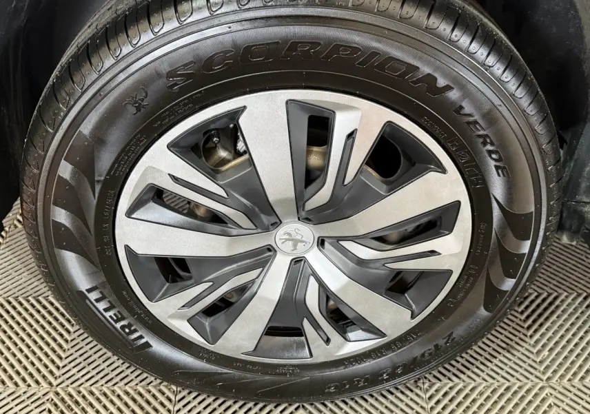 Gros plan sur la jante alliage grise et noire avec logo Peugeot au centre, montée sur pneu Pirelli Scorpion Verde.