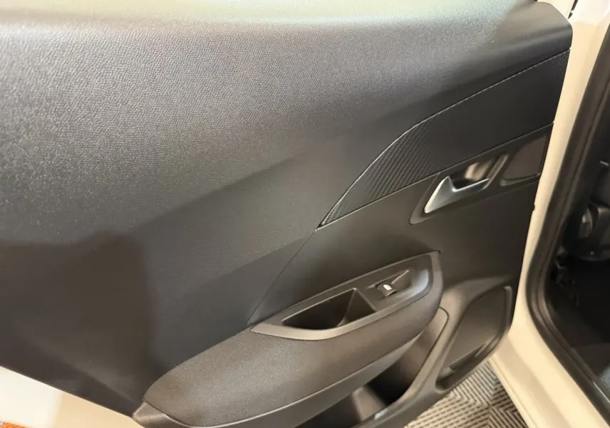 Vue rapprochée de la porte arrière gauche noire du Peugeot 2008 blanc, avec poignée et commande de vitre intégrée.