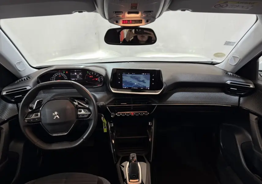 Vue intérieure avant du tableau de bord noir du Peugeot 2008 avec écran tactile central et volant cuir multifonctions.