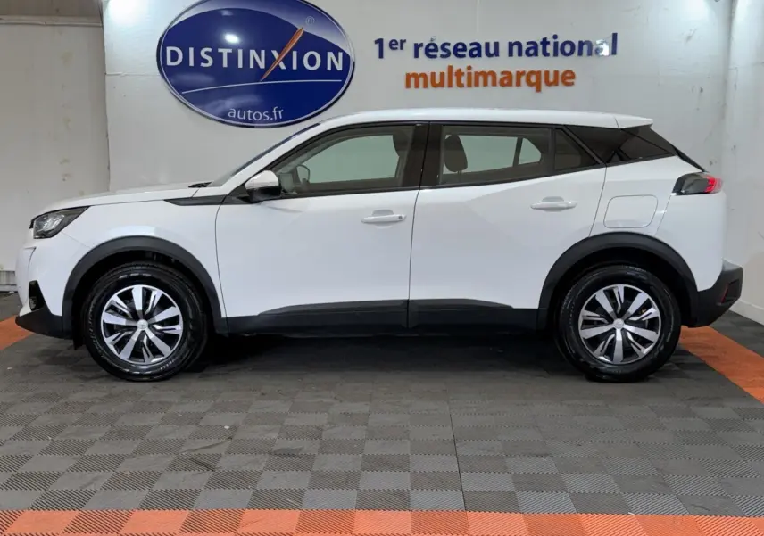 Peugeot 2008 blanc vue de profil côté gauche, avec jantes alliage et toit noir contrastant en intérieur showroom.