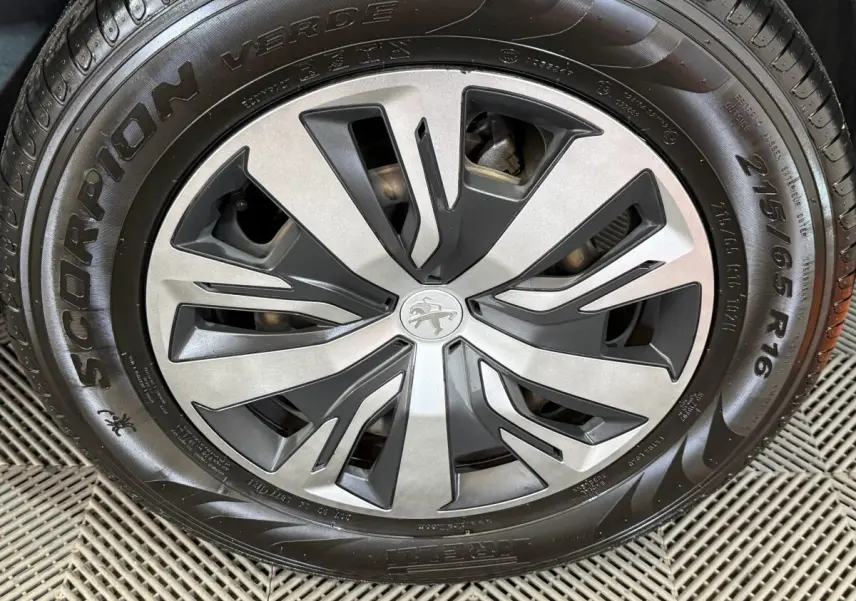 Gros plan sur la jante alliage gris et noir avec logo Peugeot au centre, montée sur pneu Pirelli Scorpion Verde.