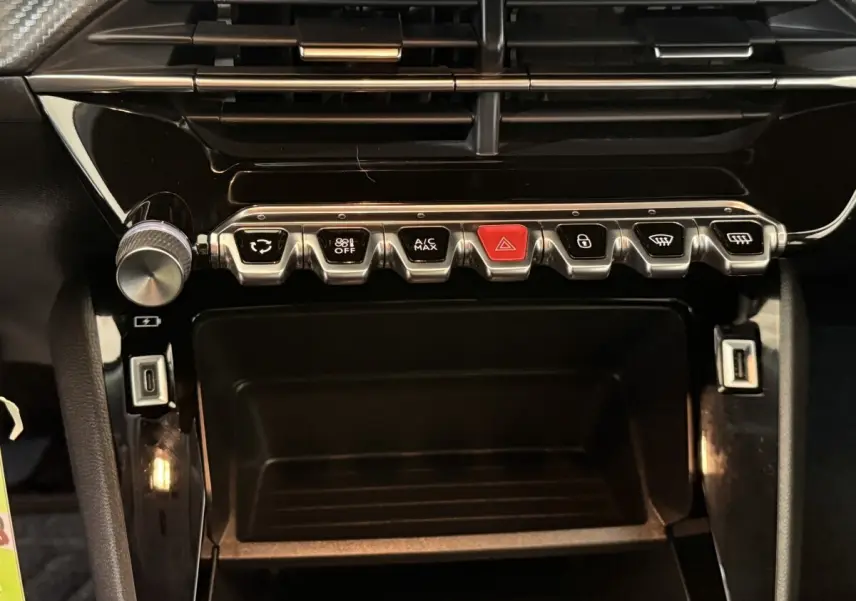 Vue rapprochée de la console centrale noire du Peugeot 2008 avec boutons de commande et ports USB visibles.