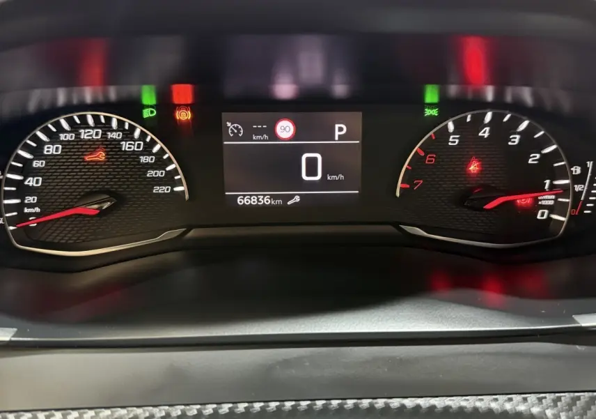 Vue rapprochée du tableau de bord numérique du Peugeot 2008 blanc, affichant 66 836 km et indicateurs allumés.