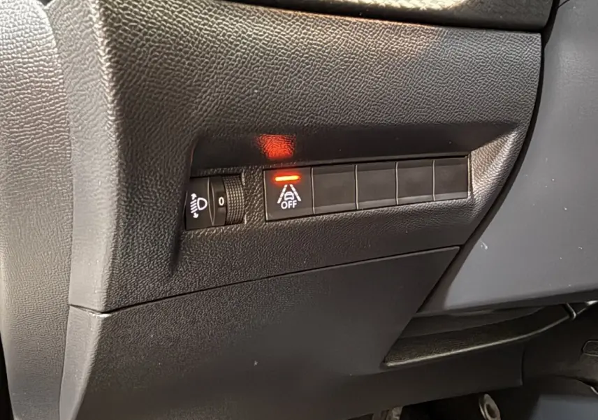 Détail du tableau de bord noir côté gauche avec commande d'éclairage et bouton d'alerte de franchissement de ligne allumé sur Peugeot 2008.