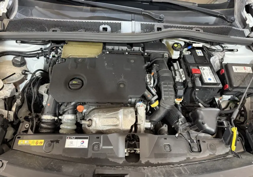 Vue plongeante sur le moteur diesel d'une Peugeot 2008 blanche, version BlueHDi 130 avec capot ouvert.
