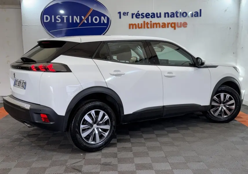 Vue 3/4 arrière droite d'un Peugeot 2008 blanc, avec détails noirs contrastants et jantes alliage bicolores.